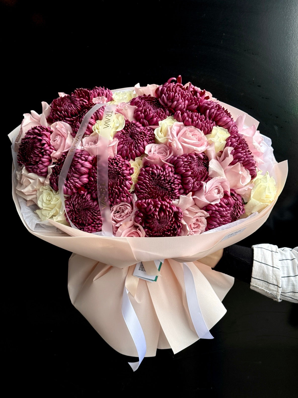 Buchet de flori elegant cu crizanteme mov, trandafiri roz și trandafiri albi, ambalat în material bej cu panglici albe de la Floraria Oradea TRAVA