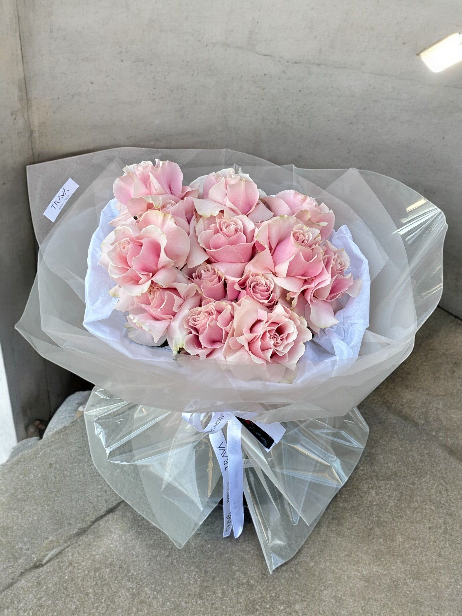 Buchet elegant de trandafiri roz, aranjat cu grijă în folie transparentă, perfect pentru a celebra feminitatea și frumusețea de 1 și 8 Martie, disponibil la TRAVÁ Atelier Floral cu livrare gratuită în Oradea.