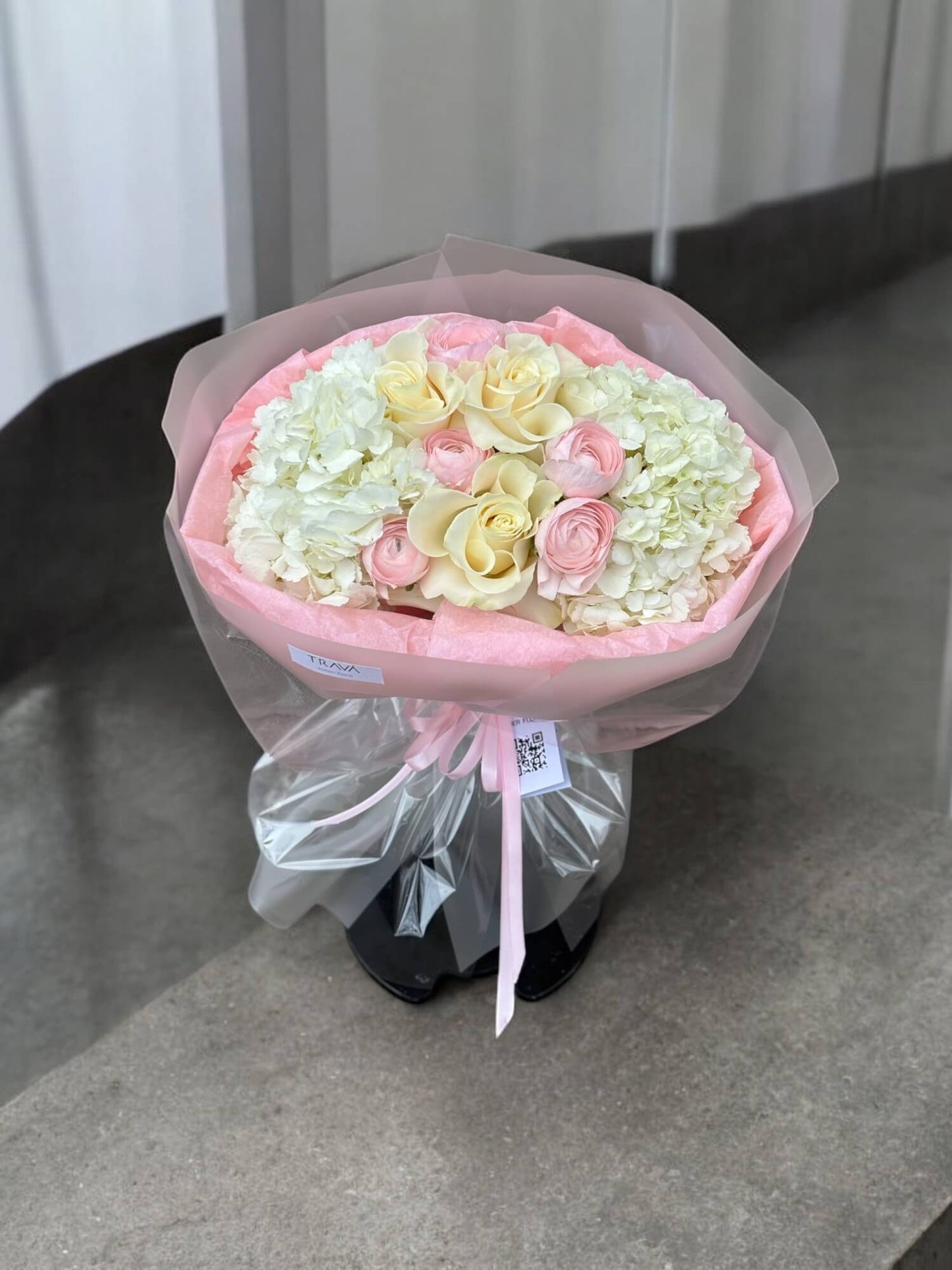 Buchet din hortensie alba, trandafiri albi si ranunculus roz in ambalaj alb semi-transparent cu panglica de satin