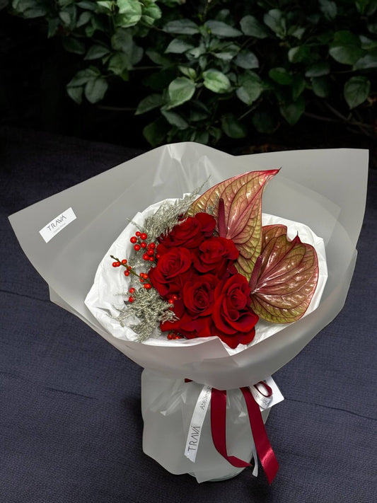 Buchet din trandafiri rosii, anthurium, ilex si asparagus in ambalaj alb cu panglica de satin si hrana pentru flori. Perfet pentru un cadou de iarna, comanda online cu livrare gratuita in Oradea sau cu ridicare de la florarie online Oradea Trava Atelier Floral