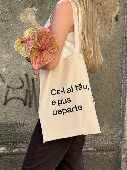 Tote bag natur TRAVÁ din bumbac 100%, purtată pe umăr, cu mesaj imprimat Ce-i al tău, e pus departe.
