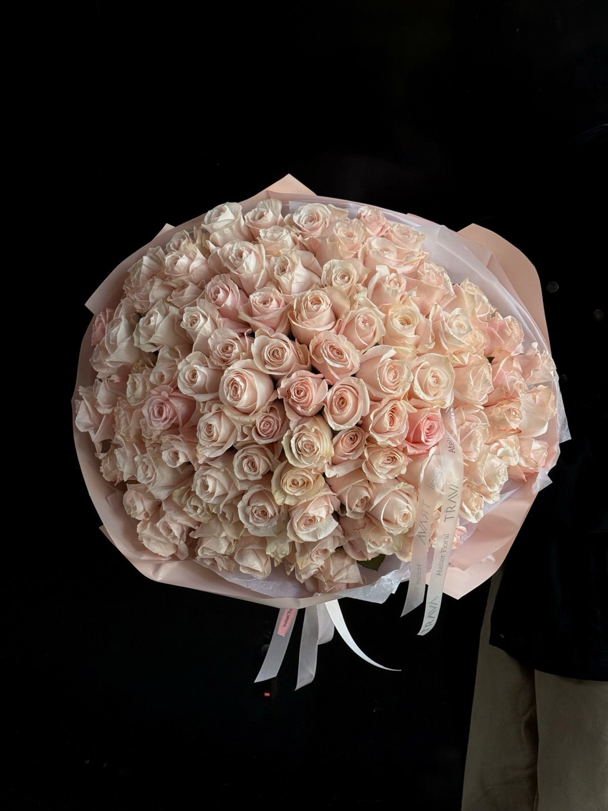 Buchet mare cu 101 trandafiri roz pal, ambalat elegant în hârtie roz deschis, realizat de TRAVA florărie Oradea