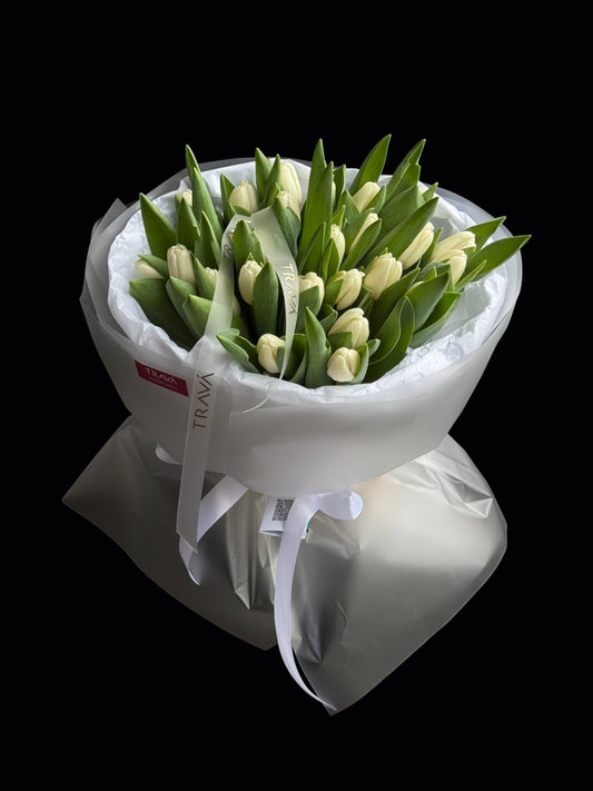 Buchet bogat cu 25 de lalele albe proaspete ambalat in hartie alba si legat cu panglica personalizata Trava Atelier cu livrare gratuita la domiciliu.