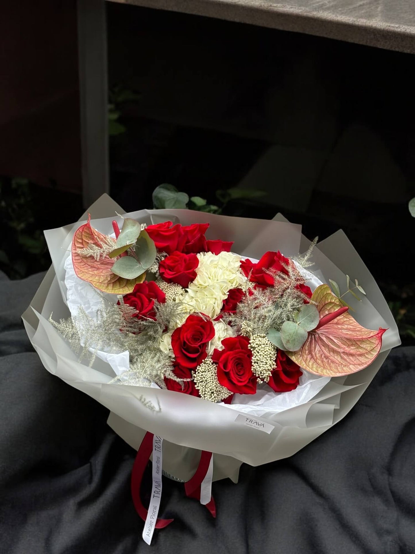 Buchet de flori care contine: trandafiri rosii, anthurium, hortensii, eucalipt si asparagus. Ambalat in folie alba cu panglica de satin si hrana pentru flori. Ideal pentru orice ocazie comanda acum cu livrare gratuita in Oradea sau cu ridicare din florarie online Oradea Trava Atelier Floral