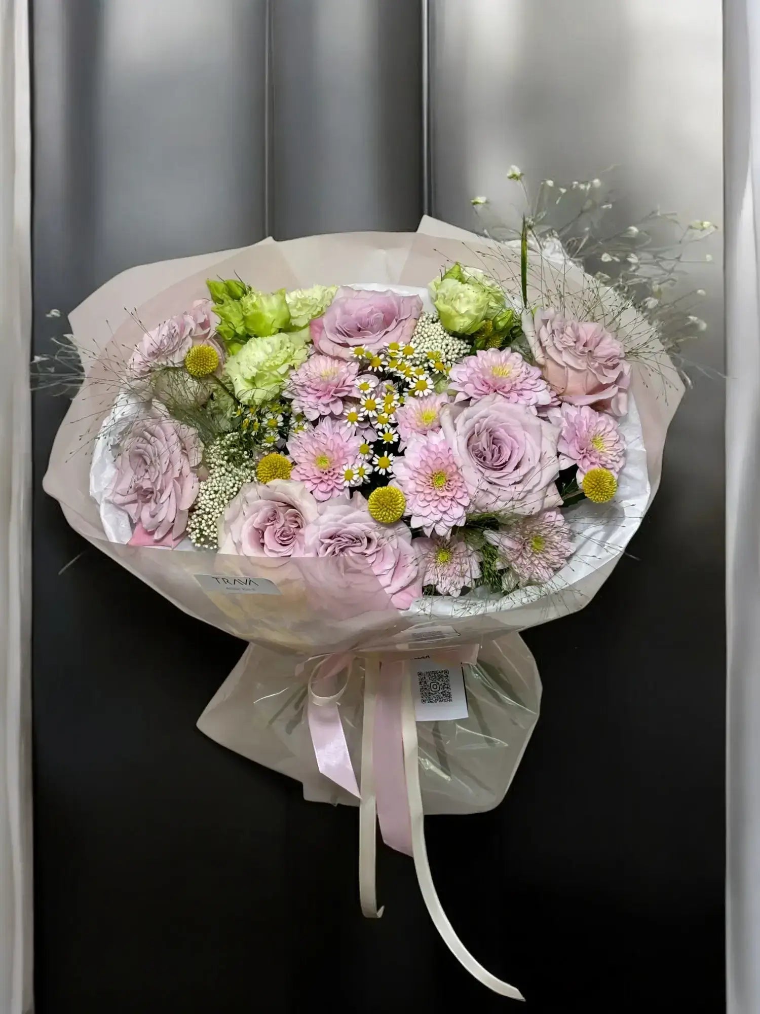 Buchet elegant pastelat cu trandafiri roz, crizanteme, lisianthus, panicum, ozothamnus, craspedia și mușețel, ambalat în alb cu panglică roz, disponibil pentru comandă online și livrare gratuită din florarie Oradea, TRAVÁ Atelier Floral.