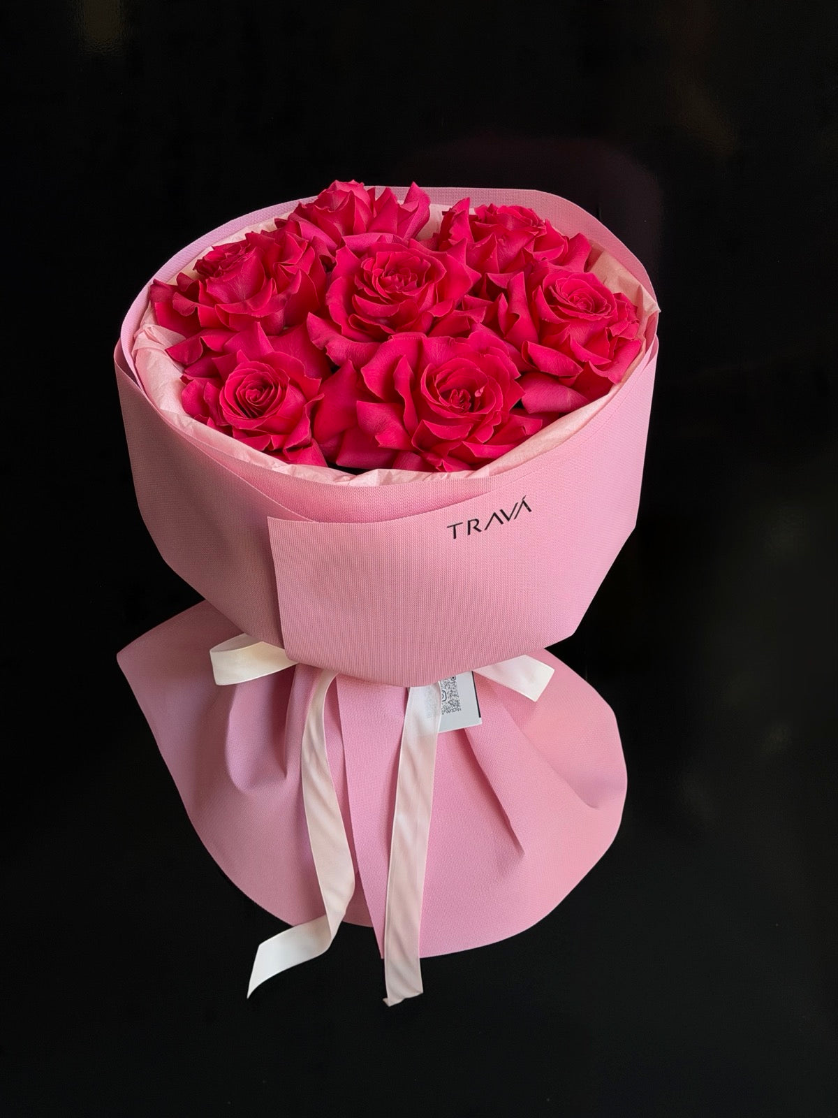 Buchet rotund din trandafiri fucsia în hârtie roz cu logo TRAVÁ, legat cu fundă din panglică ivory – florărie Oradea TRAVA ATELIER