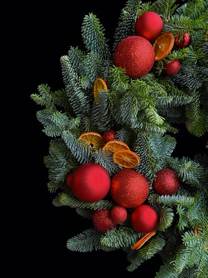 Detaliu coroniță de Crăciun cu conifere, globuri roșii și portocale deshidratate de la TRAVA