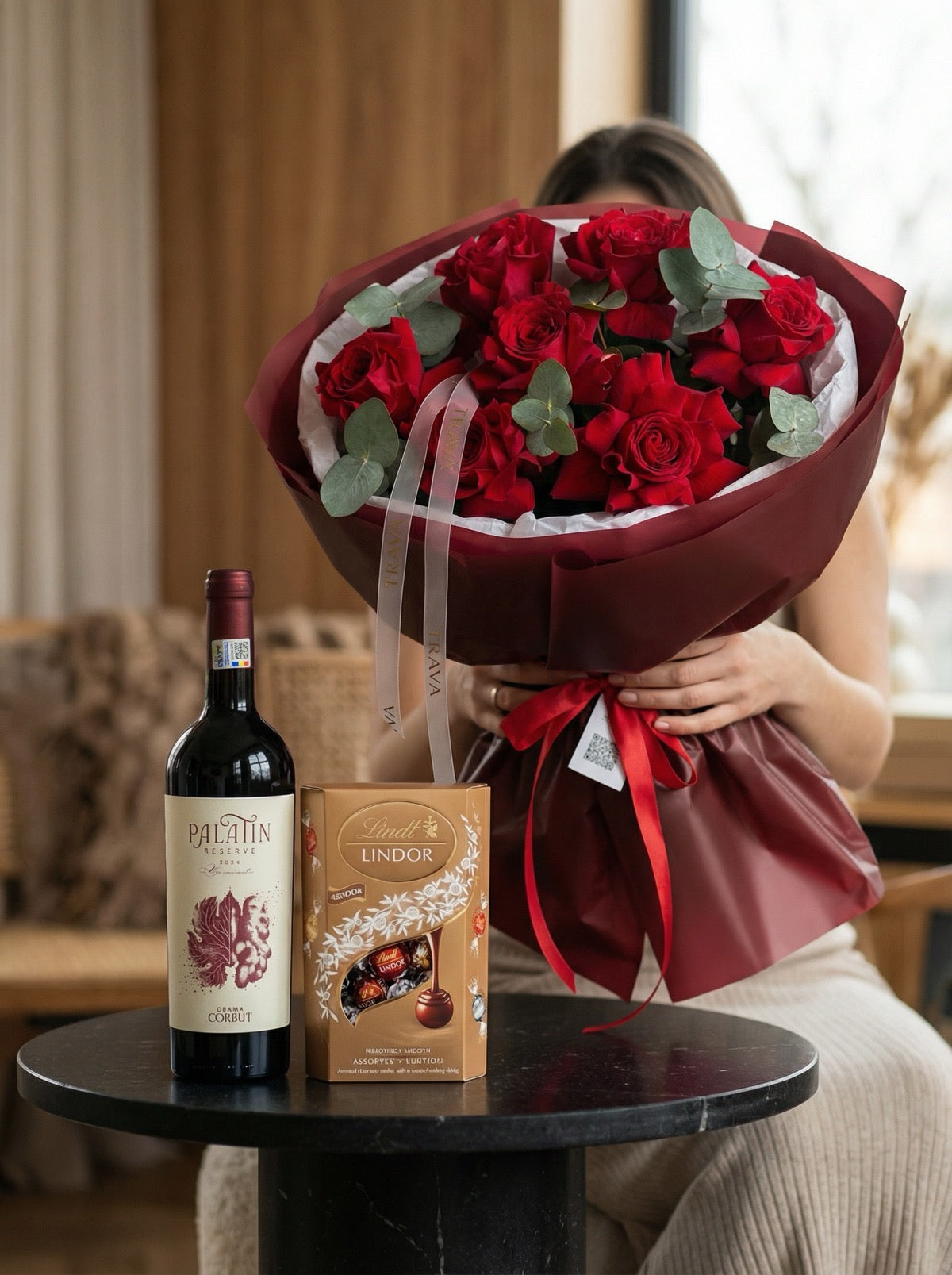 Pachet cadou premium Valentine's Day cu buchet de 7 trandafiri roșii flexați, vin roșu Palatin Reserve Crama Corbuț și ciocolată Lindor, oferit de Trava Atelier Floral Oradea.